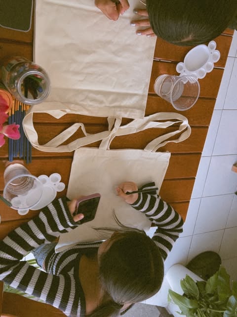 Clientas pintando tote bags en una mesa de la cafetería